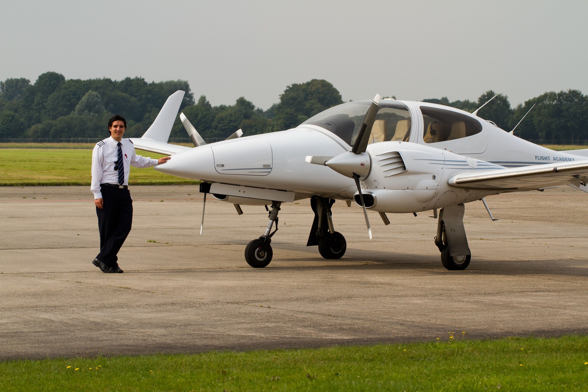 Happy student pilot standing next to a flight school aircraft